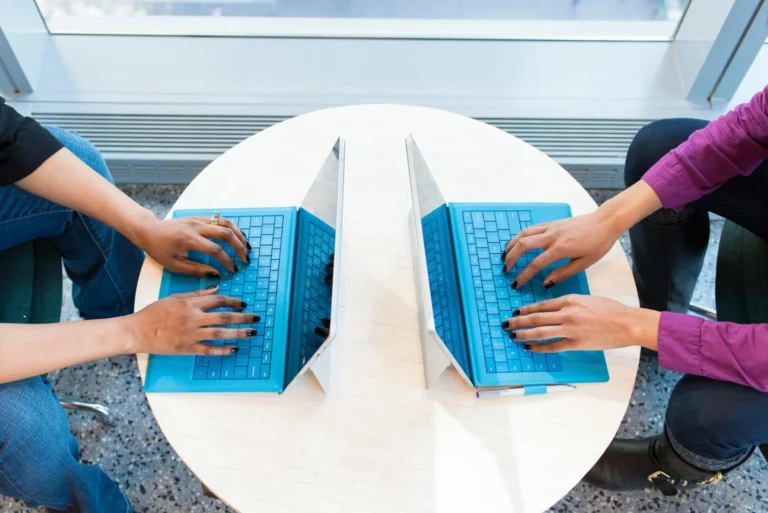 Two people working on laptops face-to-face, highlighting the role of technology in digital team building