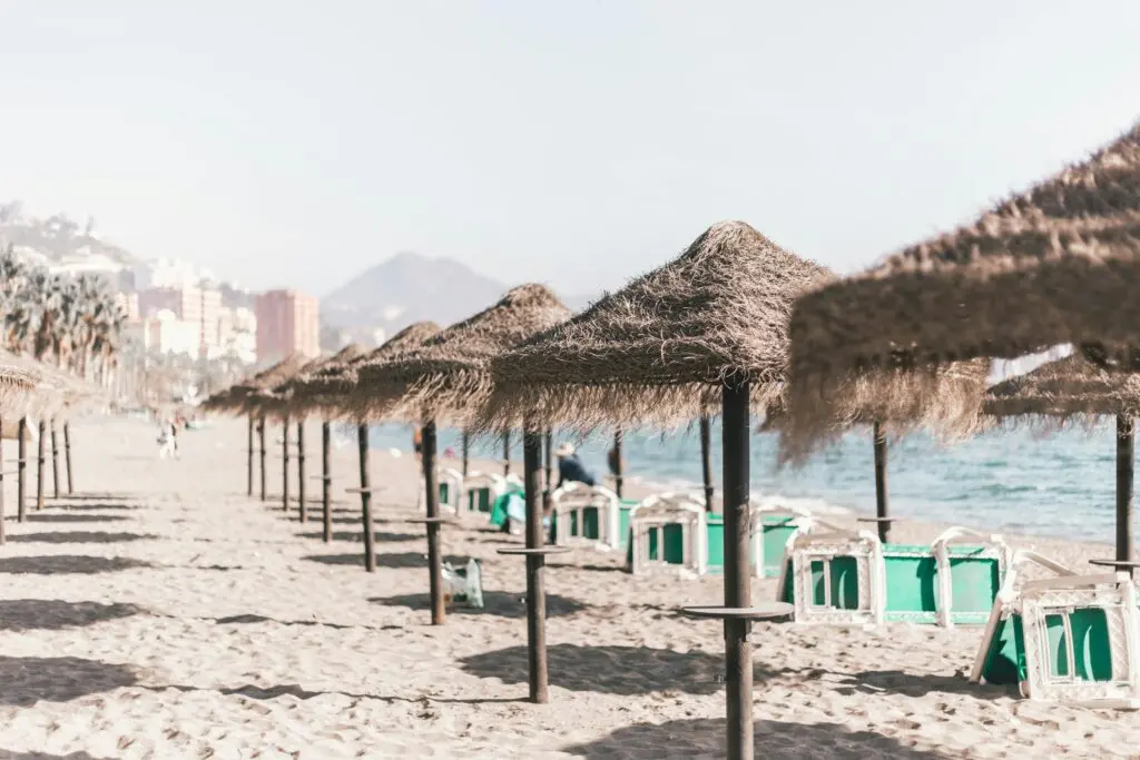 Vista de una playa con sombrillas de paja en España, destacando los destinos costeros ideales para el turismo MICE