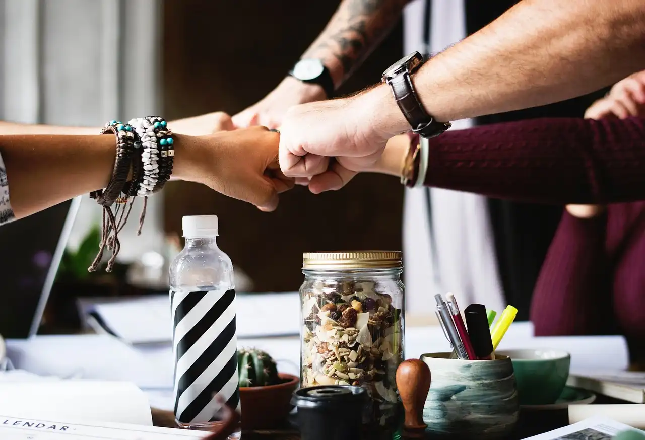 Blog resources teambuilding companies: team collaborating and connecting with a fist bump during a teambuilding event